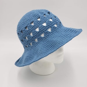 May include: A blue crocheted sun hat with a wide brim and a geometric pattern. The hat has a crocheted design with open spaces.
