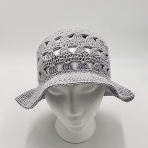 May include: A grey crocheted sun hat with a wide brim and a lacy design.