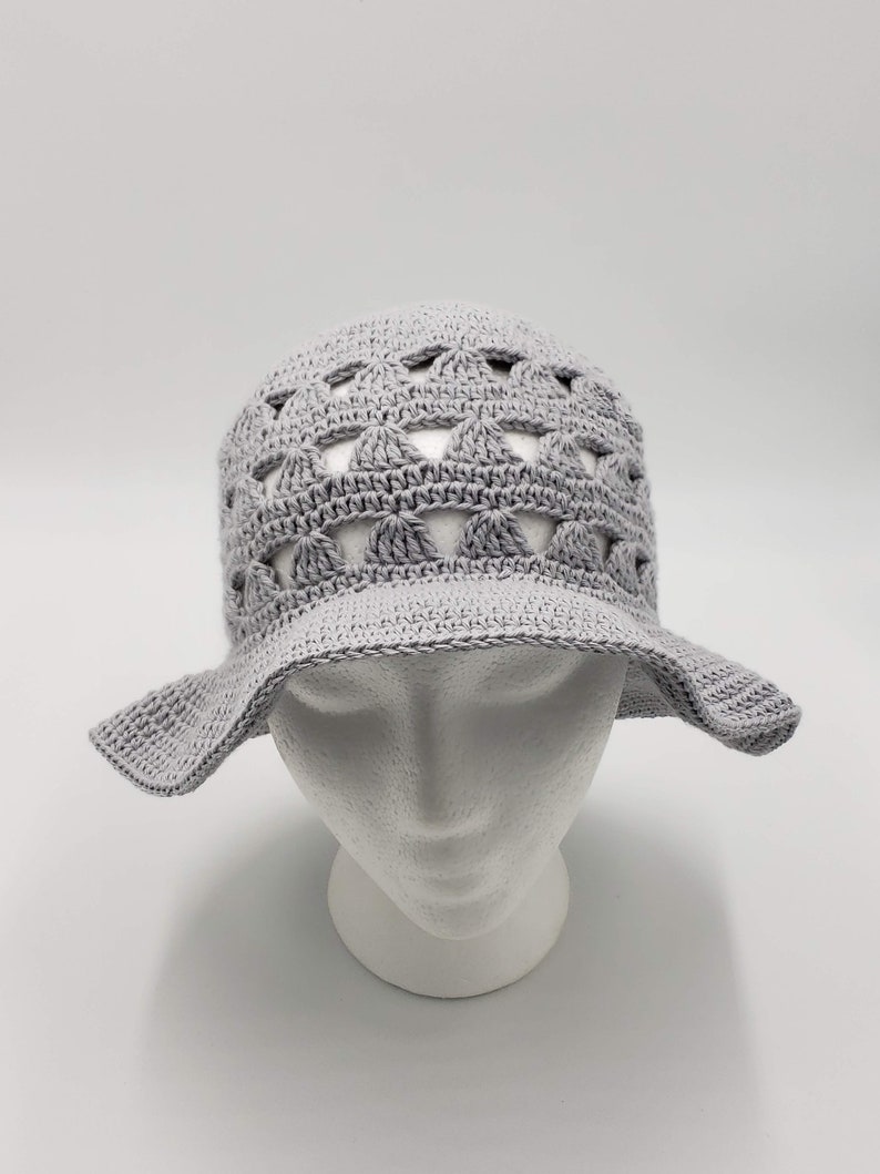 May include: A grey crocheted sun hat with a wide brim and a lacy design.