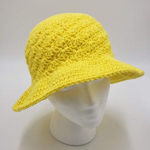 May include: A bright yellow crocheted sun hat with a wide brim.