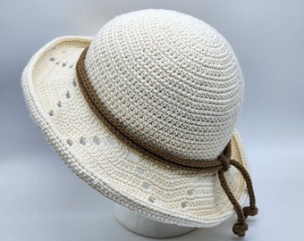 May include: A white crocheted sun hat with a brown crocheted band and ties.