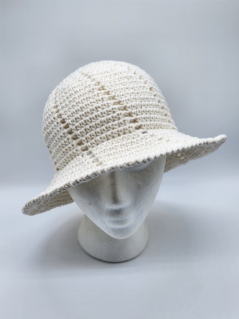 May include: A white crocheted sun hat with a wide brim. The hat is made with a delicate open stitch pattern.