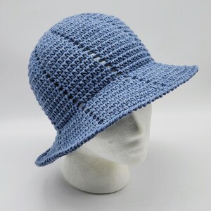 May include: A light blue crocheted sun hat with a wide brim. The hat is made with a simple stitch pattern and has a slightly slouchy fit.