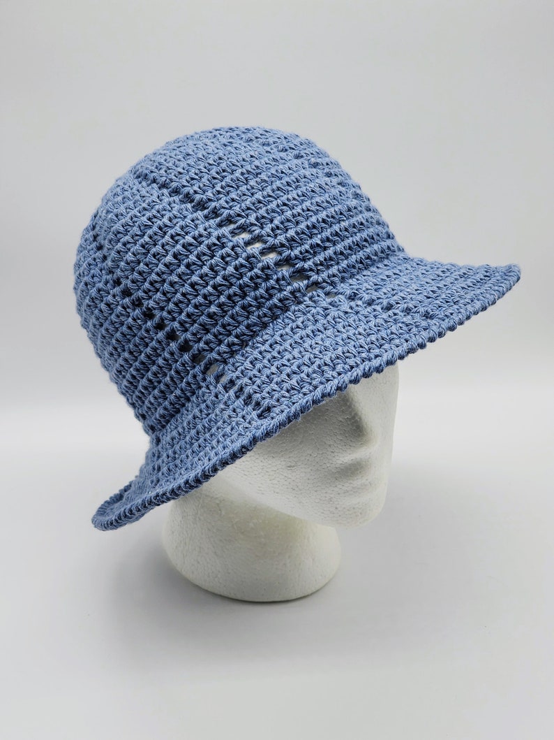 May include: A light blue crocheted sun hat with a wide brim. The hat is made with a simple stitch pattern and has a slightly slouchy fit.
