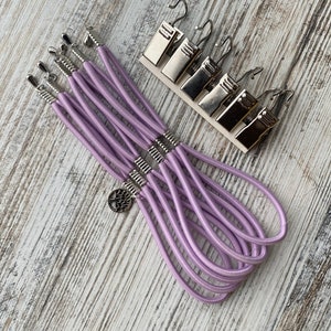 May include: A set of six lavender elastic cord bracelets with silver metal clasps and a tree charm.