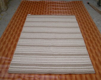May include: A white and brown patterned rug with a woven texture. The rug has a subtle geometric design with brown stripes and white accents.