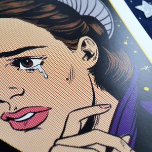 May include: A close-up of a woman's face in a comic book style. She has dark hair and is wearing a purple and black outfit. Her eye is tearful and her mouth is slightly open. The background is a yellow and black pattern.