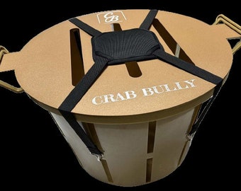 May include: A tan-colored crab trap with a black padded strap system and the text "CRAB BULLY" printed on the top.