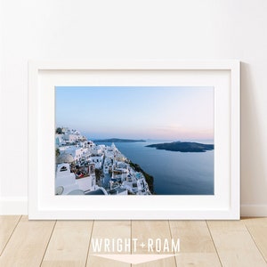 Coastal decor featuring a blue sunset in Santorini Greece. This photograph shows the aegean sea and caldera views in the background and white city buildings of Fira in the foreground.