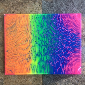 May include: A rectangular canvas painting featuring a vibrant rainbow gradient created with fluid acrylic paint. The design transitions from orange on the left to yellow, bright green, blue, and pink on the right, showcasing intricate cell patterns.