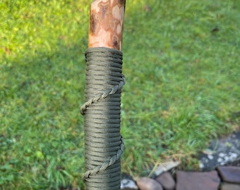 This 46” Hazel Hiking Stick: it has a spiral paracord hand grip/wrist strap, a smooth angled thumb rest and a nice straight strong shaft