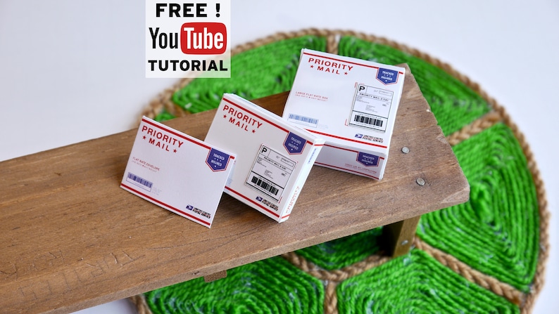 May include: Three white and red Priority Mail boxes of varying sizes are arranged on a wooden surface. The boxes have labels and barcodes. The image also includes the text "FREE! YouTube TUTORIAL".
