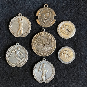 Seven 1950s Vintage High School Athletic Medals -- Swimming (2), Golf, Skiing, Majorette, Suburban Athletic League, Eastern District