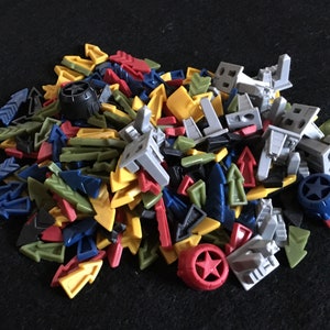 May include: A pile of colorful plastic game pieces, including arrows, stars, and small figures. The pieces are in various shades of blue, green, yellow, red, and gray.