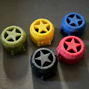 May include: Five plastic star-shaped caps in different colors: green, yellow, blue, red, and black. Each cap has a five-pointed star cut out in the center.