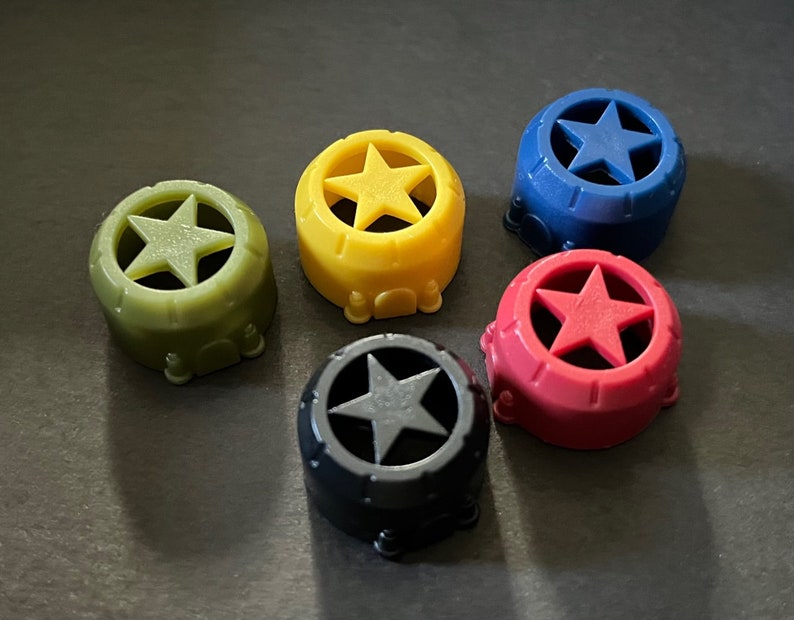 May include: Five plastic star-shaped caps in different colors: green, yellow, blue, red, and black. Each cap has a five-pointed star cut out in the center.