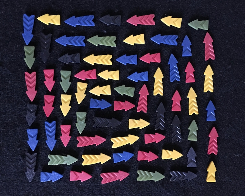 May include: A collection of colorful arrow-shaped tiles in red, yellow, blue, green, and black. The tiles are arranged in a grid pattern on a black surface.