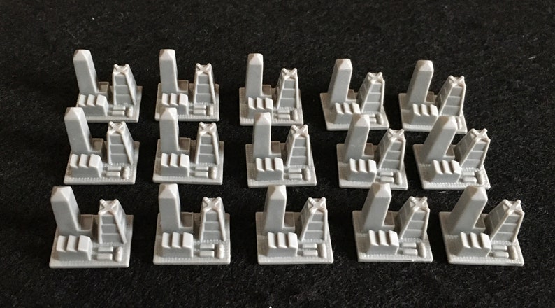 May include: Set of 18 gray plastic building pieces for a board game. Each piece features a tall tower with a cross on top and a smaller building with a flat roof.