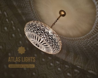 May include: A gold Moroccan pendant light with a decorative, intricate, geometric pattern. The light is hanging from a chain and has a round, dome-shaped shade.