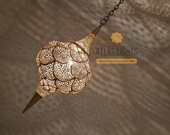 May include: A gold Moroccan pendant light with a unique, intricate design. The light is hanging from a chain and has a pointed tip.
