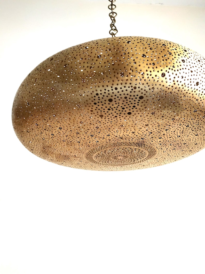 Moroccan Brass Lantern Chandelier with Stunning Light Pattern
Bring the magic of Marrakesh into your home with this magnificent, handcrafted Moroccan Brass Pendant Light. Known for its exquisite craftsmanship, this lamp is meticulously hand-punched, allowing light to filter through a myriad of small perforations to cast an immersive, spectacular, starburst pattern of light and shadow on your walls and ceiling.