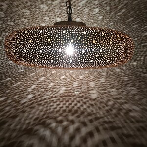 Moroccan Brass Lantern Chandelier with Stunning Light Pattern
Bring the magic of Marrakesh into your home with this magnificent, handcrafted Moroccan Brass Pendant Light. Known for its exquisite craftsmanship, this lamp is meticulously hand-punched, allowing light to filter through a myriad of small perforations to cast an immersive, spectacular, starburst pattern of light and shadow on your walls and ceiling.