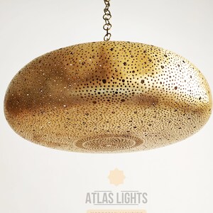 May include: A gold-toned, round, hanging pendant light fixture with a decorative, perforated pattern. The light fixture is suspended from a chain.