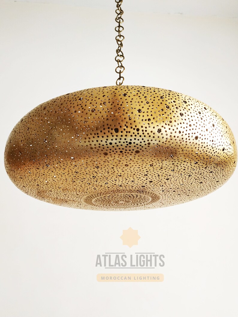 May include: A gold-toned, round, hanging pendant light fixture with a decorative, perforated pattern. The light fixture is suspended from a chain.