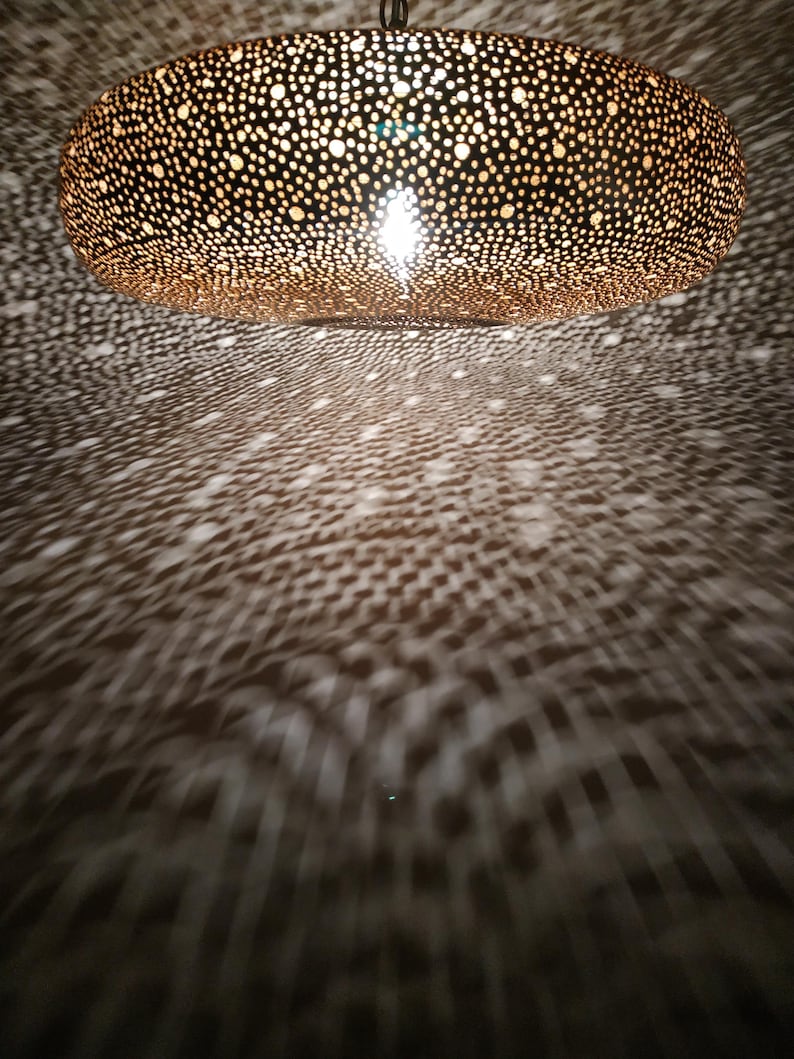 Moroccan Brass Lantern Chandelier with Stunning Light Pattern
Bring the magic of Marrakesh into your home with this magnificent, handcrafted Moroccan Brass Pendant Light. Known for its exquisite craftsmanship, this lamp is meticulously hand-punched, allowing light to filter through a myriad of small perforations to cast an immersive, spectacular, starburst pattern of light and shadow on your walls and ceiling.