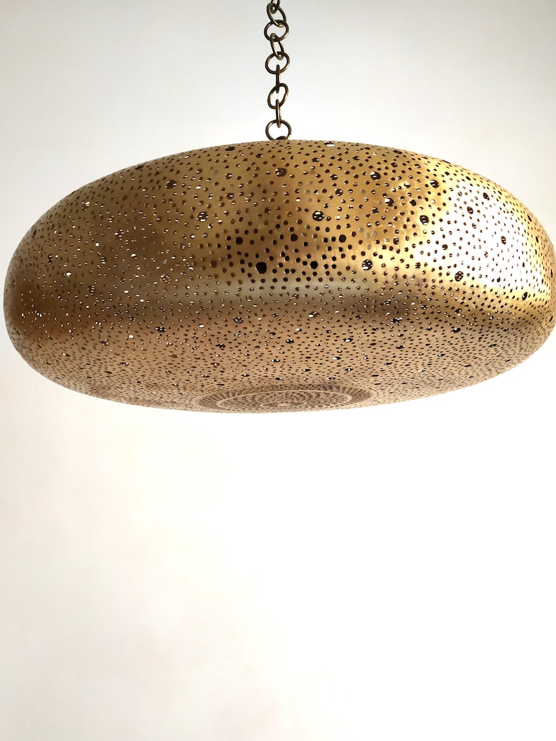 Moroccan Brass Lantern Chandelier with Stunning Light Pattern
Bring the magic of Marrakesh into your home with this magnificent, handcrafted Moroccan Brass Pendant Light. Known for its exquisite craftsmanship, this lamp is meticulously hand-punched, allowing light to filter through a myriad of small perforations to cast an immersive, spectacular, starburst pattern of light and shadow on your walls and ceiling.