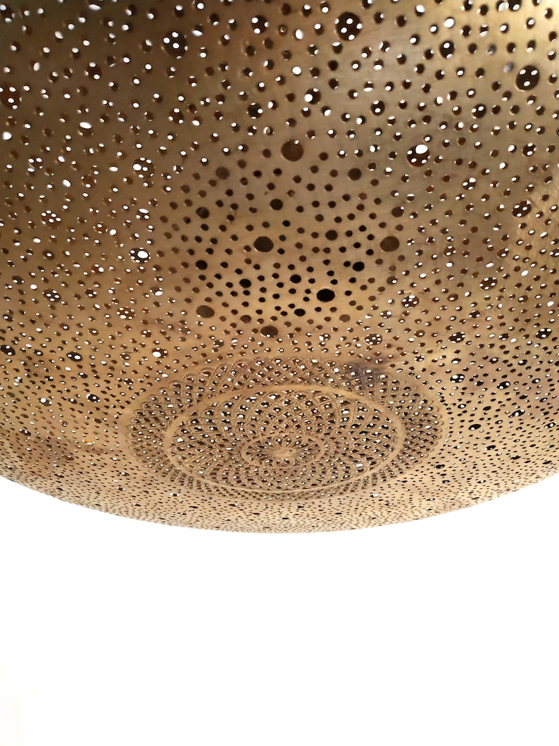 Moroccan Brass Lantern Chandelier with Stunning Light Pattern
Bring the magic of Marrakesh into your home with this magnificent, handcrafted Moroccan Brass Pendant Light. Known for its exquisite craftsmanship, this lamp is meticulously hand-punched, allowing light to filter through a myriad of small perforations to cast an immersive, spectacular, starburst pattern of light and shadow on your walls and ceiling.