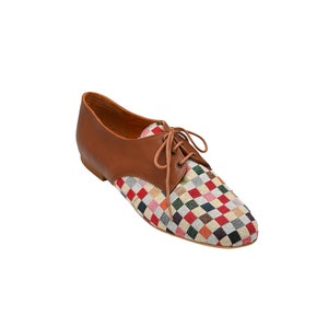 May include: A brown leather oxford shoe with a colorful checkered fabric toe. The shoe has brown laces and a low heel. The checkered pattern includes red, green, blue, and yellow squares.