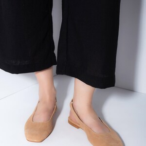 K&ouml;nnte beinhalten: Ein Paar hellbraune Slipper aus Wildleder mit quadratischer Spitze und einem Slingback-Riemen.