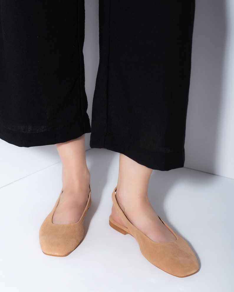K&ouml;nnte beinhalten: Ein Paar hellbraune Slipper aus Wildleder mit quadratischer Spitze und einem Slingback-Riemen.