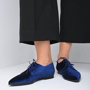 May include: A pair of blue velvet lace-up shoes with pointed toes. The shoes have a low heel and are made of a soft, comfortable material.