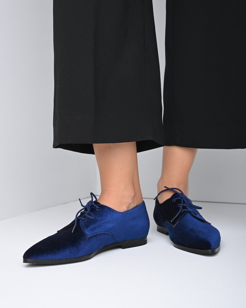 May include: A pair of blue velvet lace-up shoes with pointed toes. The shoes have a low heel and are made of a soft, comfortable material.