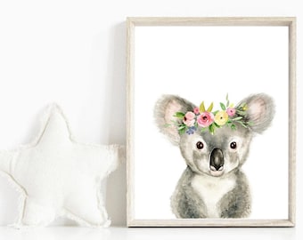 May include: A watercolor painting of a koala wearing a flower crown. The koala is gray with a white chest and has a sweet expression. The flowers in the crown are pink, yellow, and white.