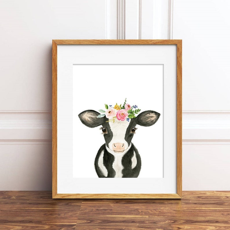 Puede incluir: Una vaca negra y blanca con una corona de flores rosa, amarilla y azul. La vaca est&aacute; mirando directamente al espectador con una expresi&oacute;n dulce.