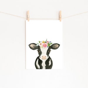 Puede incluir: Una vaca negra y blanca con una corona de flores rosas, amarillas y verdes. La vaca est&aacute; mirando directamente al espectador.