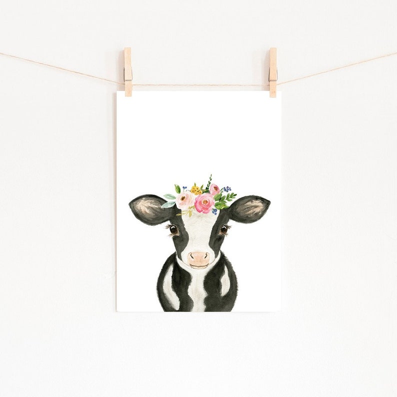 Puede incluir: Una vaca negra y blanca con una corona de flores rosas, amarillas y verdes. La vaca est&aacute; mirando directamente al espectador.