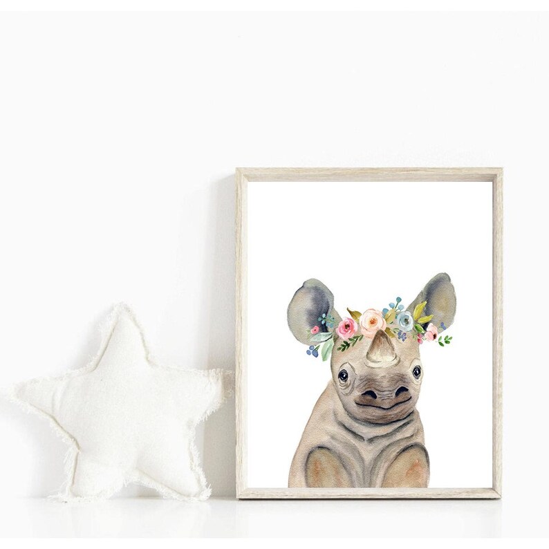 K&ouml;nnte beinhalten: Ein Aquarellbild eines Nashorns mit einer Blumenkrone. Das Nashorn ist hellbraun mit einer grauen Nase und Ohren. Die Blumenkrone besteht aus rosa, blauen und wei&szlig;en Blumen.