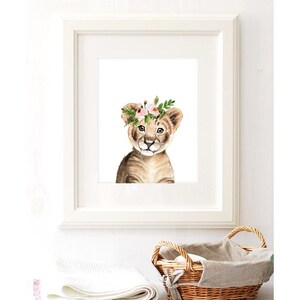 K&ouml;nnte beinhalten: Ein Aquarellbild eines L&ouml;wenjungen mit einer rosa Bl&uuml;tenkrone. Das Junge schaut den Betrachter direkt an und hat einen s&uuml;&szlig;en Ausdruck. Der Hintergrund ist wei&szlig;.