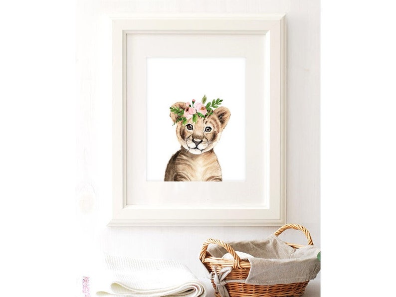 K&ouml;nnte beinhalten: Ein Aquarellbild eines L&ouml;wenjungen mit einer rosa Bl&uuml;tenkrone. Das Junge schaut den Betrachter direkt an und hat einen s&uuml;&szlig;en Ausdruck. Der Hintergrund ist wei&szlig;.
