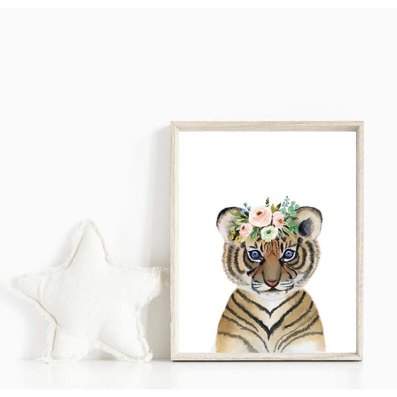 K&ouml;nnte beinhalten: Ein Aquarellbild eines Tigerbabys mit einer Blumenkrone. Das Tigerbaby hat braune und schwarze Streifen und blaue Augen. Die Blumenkrone besteht aus rosa, wei&szlig;en und gr&uuml;nen Blumen.