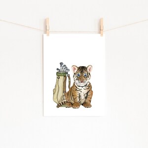 May include: A watercolor illustration of a tiger cub sitting next to a golf bag with clubs sticking out of the top.