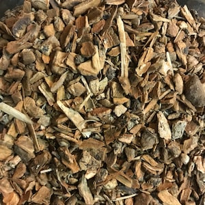 May include: Close-up of a jar filled with brown, dried bark chips. The bark is broken into small pieces and has a rough texture.