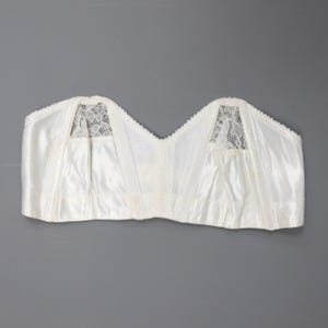 May include: White satin strapless bra with lace detailing on the cups.