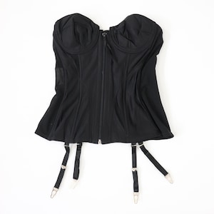 May include: Black strapless corset with a zipper closure and adjustable straps. The corset has a boned structure and a satin-like finish.