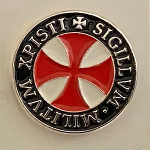 Könnte beinhalten: Eine silberne Anstecknadel mit einem schwarz-weißen Malteserkreuz mit roter Mitte. Das Kreuz ist von einem schwarzen Kreis mit den Worten "IN HOC SIGNO VINCES" und "XPISTI" in silbernen Lettern umgeben.