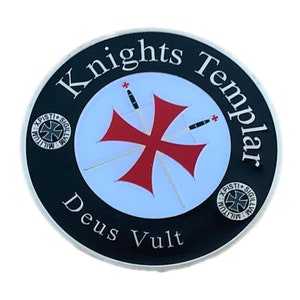 Puede incluir: Un emblema circular con las palabras "Knights Templar" en letras blancas sobre un borde negro. El emblema presenta una cruz roja, dos espadas y la frase latina "Deus Vult".